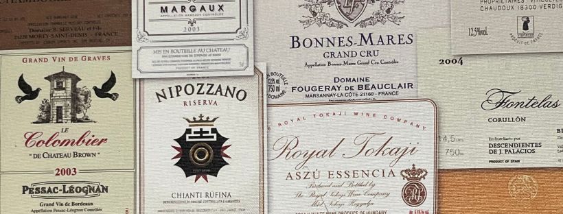 A dense collage of vintage wine labels overlapping each other, featuring ornate typography, château illustrations, and varied colors against the labels' aged paper backgrounds.